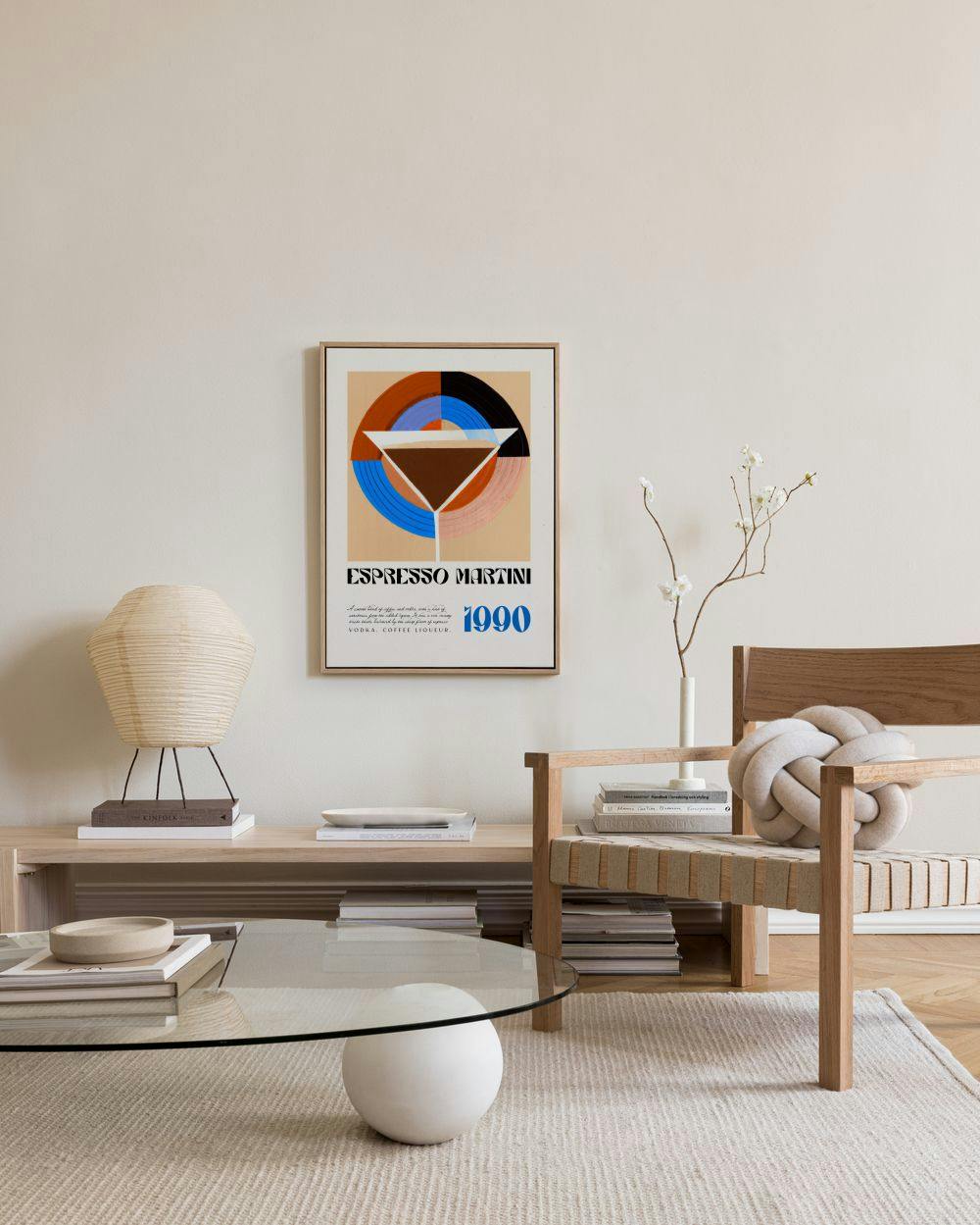 An Espresso Martini 1990 poster with a geometric martini glass design, hanging in a minimalist living room above a wooden consol