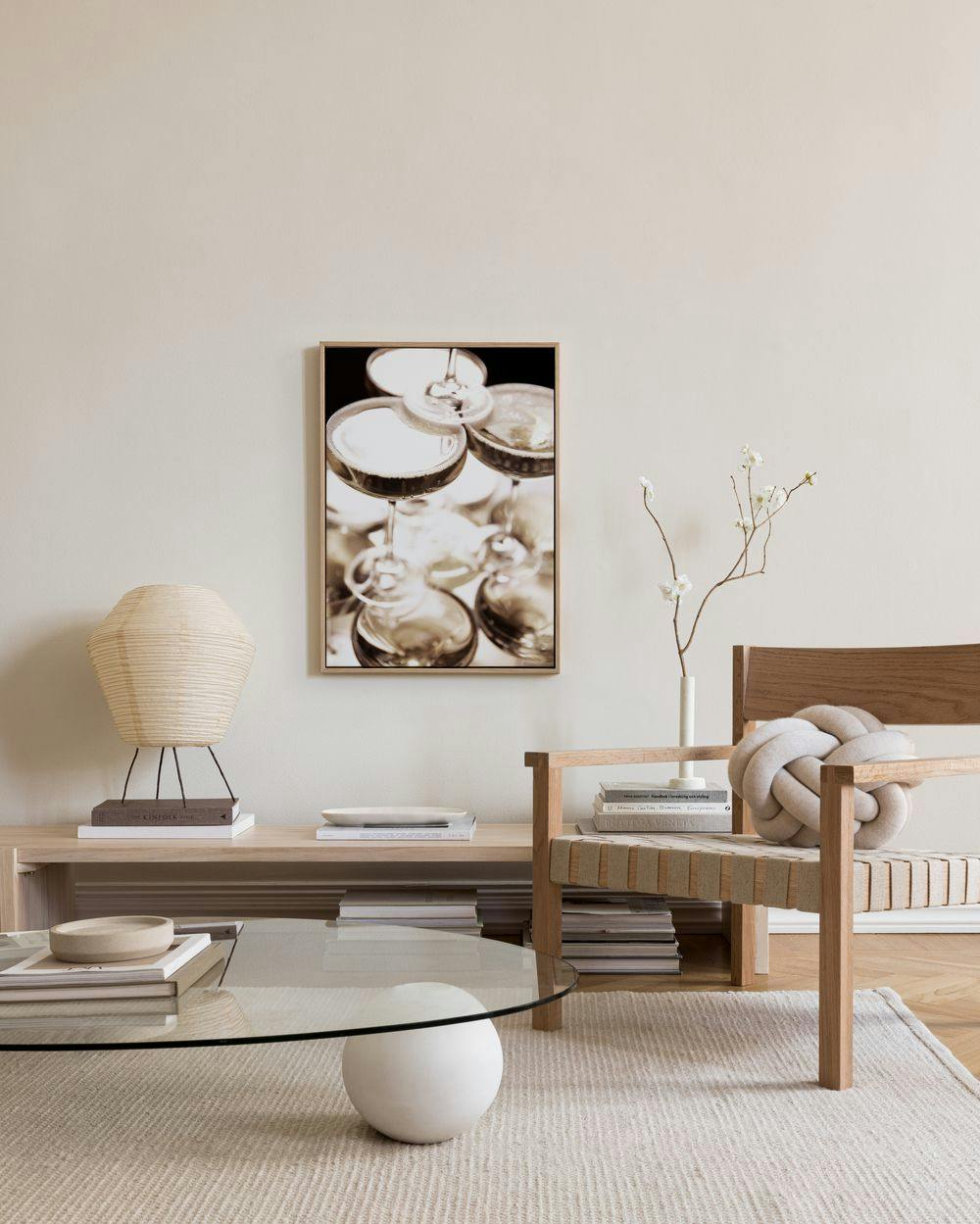 Toile de verres à cocktail empilés en noir et blanc, suspendue au-dessus dun banc en bois clair dans un salon moderne.