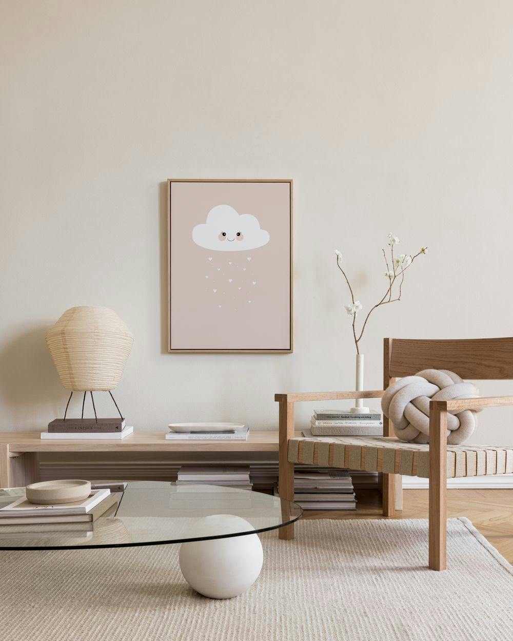 Lerretsbilde med en hvit smilende sky og små hjerter på lyserosa bakgrunn, henger i en moderne stue over et bord.