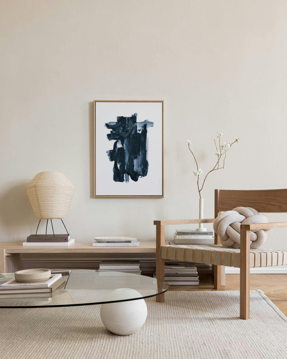 Leinwandbild mit dunkelblauen Pinselstrichen, die einen abstrakten Fleck auf weißem Grund bilden, über einem Sideboard in einem