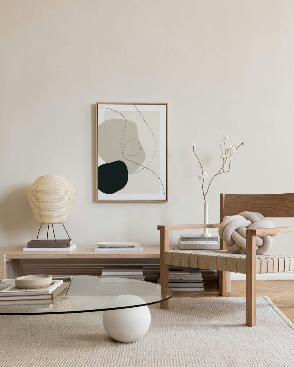 Leinwandbild mit organischen Formen in Beige, Schwarz und Grau, mit schwarzen Linien, hängt in einem modernen Wohnzimmer über ei