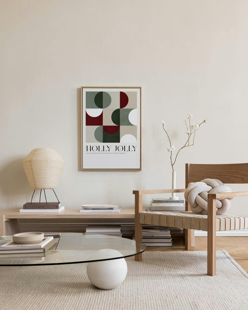 A canvas print with geometric shapes in red, green, and beige, and the text HOLLY JOLLY, hanging in a modern living room.