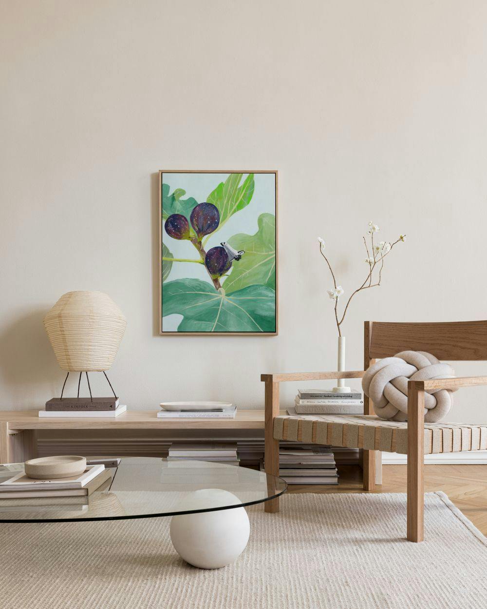 Toile murale de figues violettes sur une branche verte, exposée dans un salon moderne aux tons neutres.