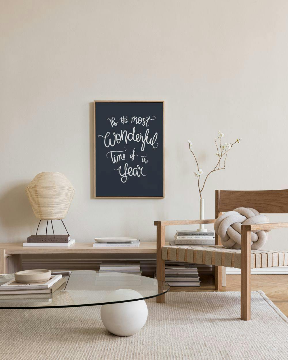 A canvas print with white cursive text Its the most wonderful time of the year on a dark blue background, hanging in a minimalis