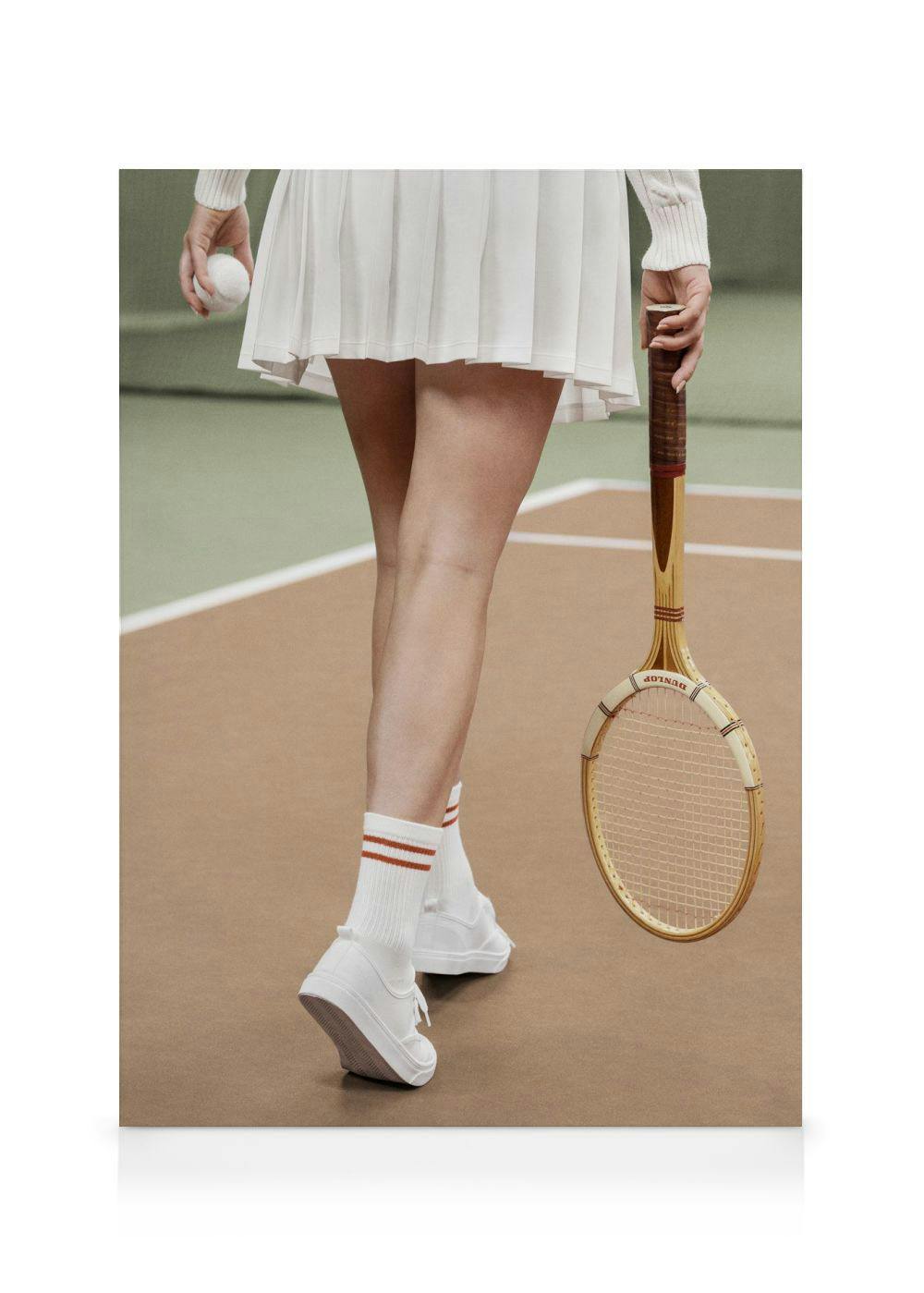 Toile Ready to Serve avec joueuse de tennis, jupe plissée blanche, chaussettes rayées, chaussures et raquette sur terre battue.