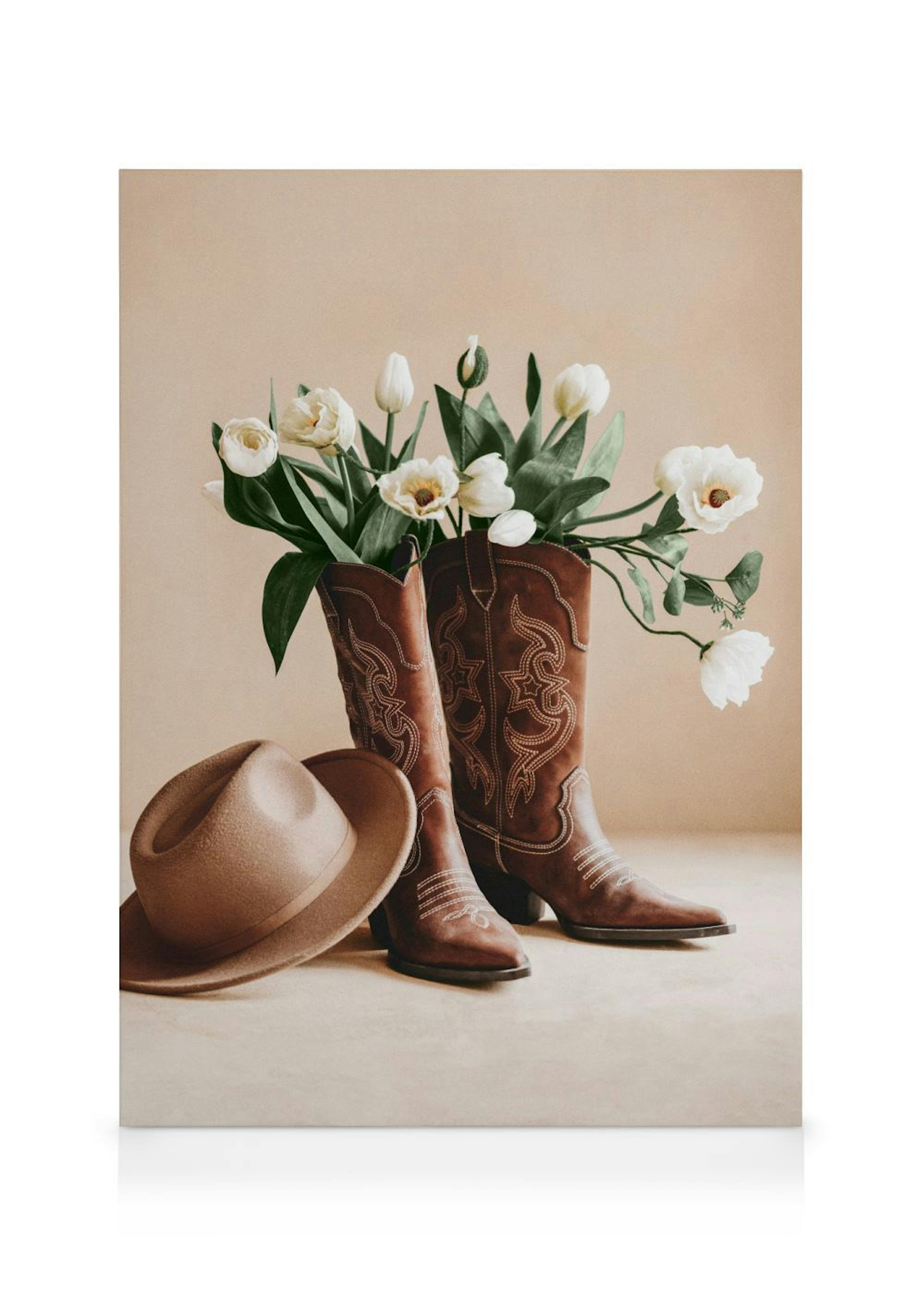 Brune cowboyboots med hvite blomster og en beige hatt på en nøytral bakgrunn. Lerret med country-stil.
