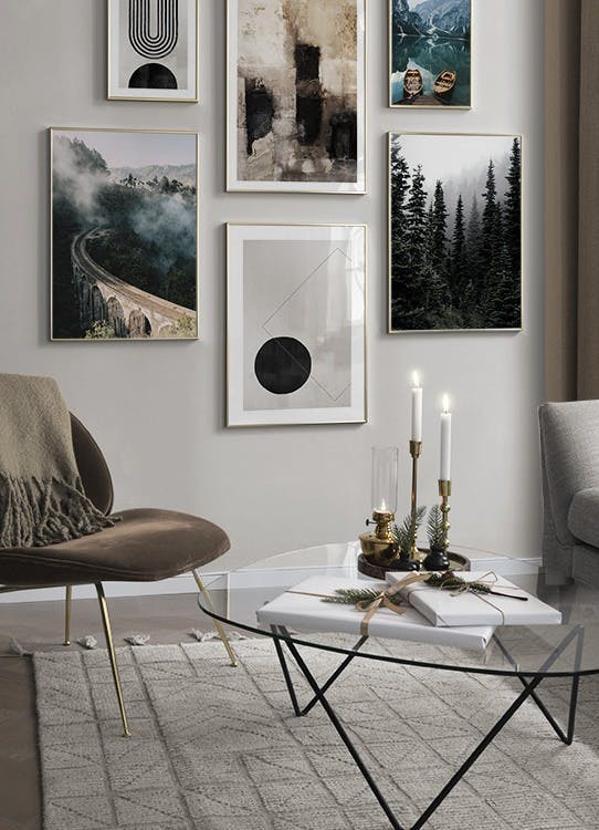 En tavelvägg med naturmotiv av skog, berg, sjö och bro, samt abstrakta mönster i svart och beige.