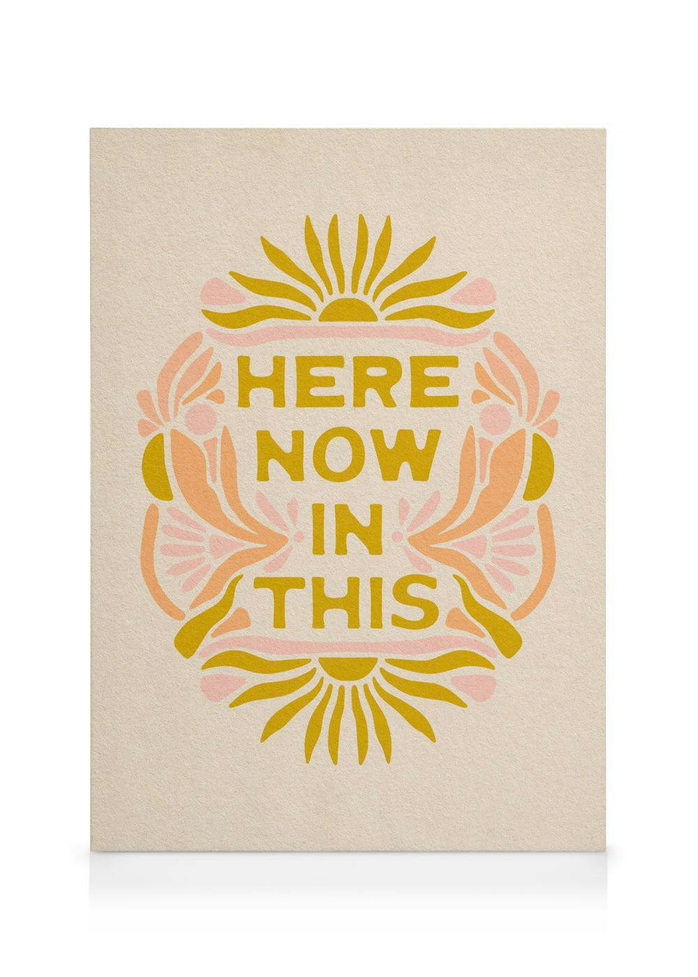 Obraz HERE NOW IN THIS se žlutým písmem, obklopený abstraktními květy a slunci v teplých barvách.