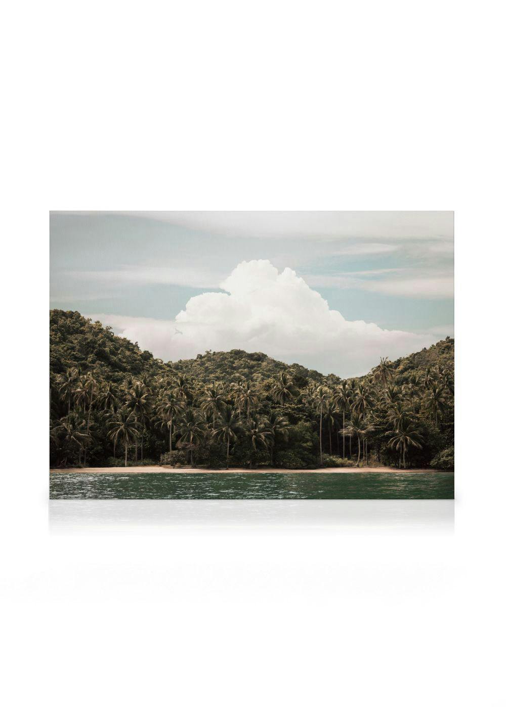 A canvas print featuring a serene tropical beach with lush hills of palm trees, calm turquoise water, and a light blue sky with