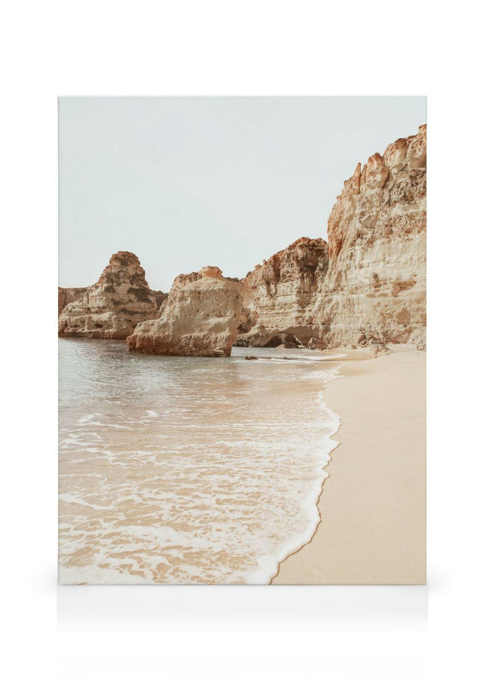 Algarve beach canvas print featuring sandy shore, gentle waves, and layered rock formations under a pale sky.