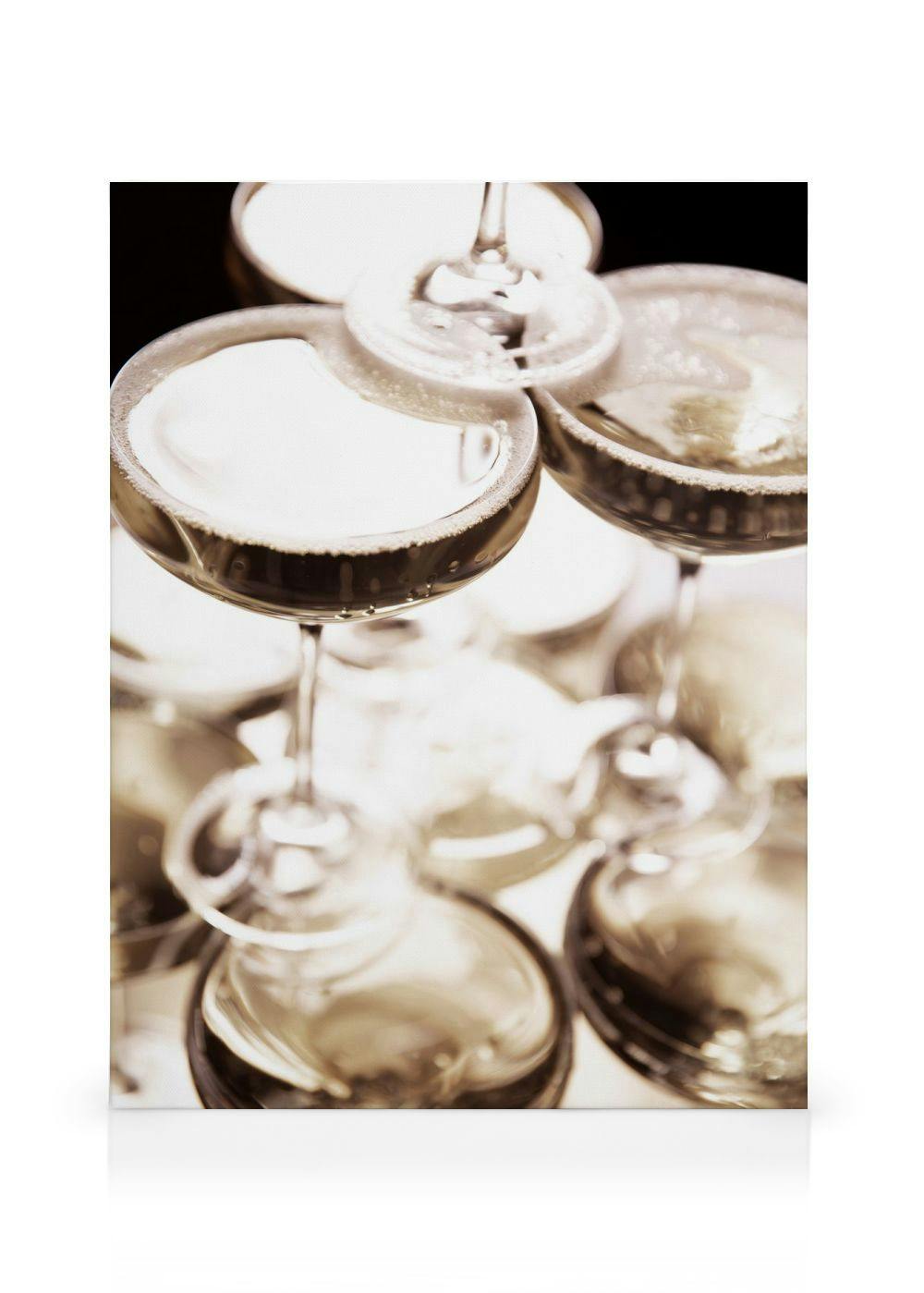 Toile avec des verres à pied de champagne empilés, liquide foncé et reflets lumineux, sur fond blanc. Typographie festive.