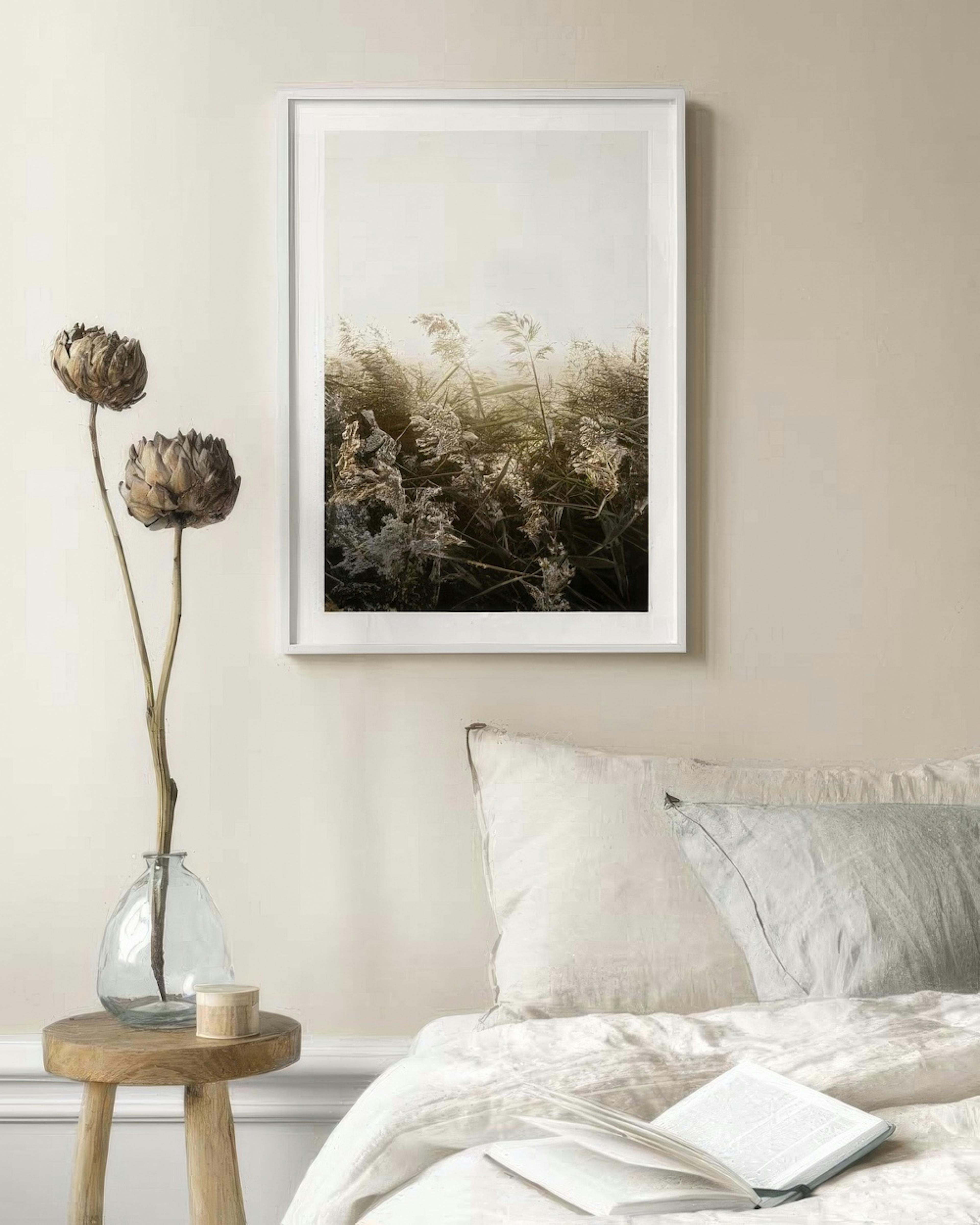 Poster mit sonnenbeschienenem Schilf, aufgehängt über einem Bett in einem Schlafzimmer.