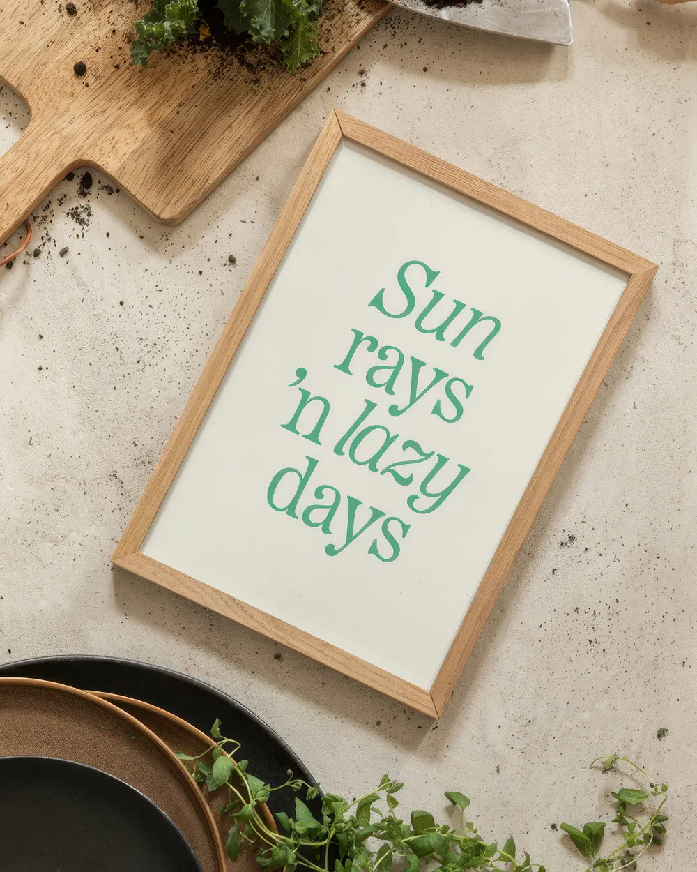 Poster con scritta verde Sun rays n lazy days su sfondo bianco, affiancato da un tagliere e piatti.
