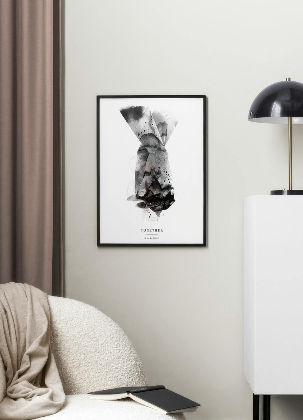 A personalised print of abstract hands holding, in black, white, and grey tones, hanging above a white armchair in a room.