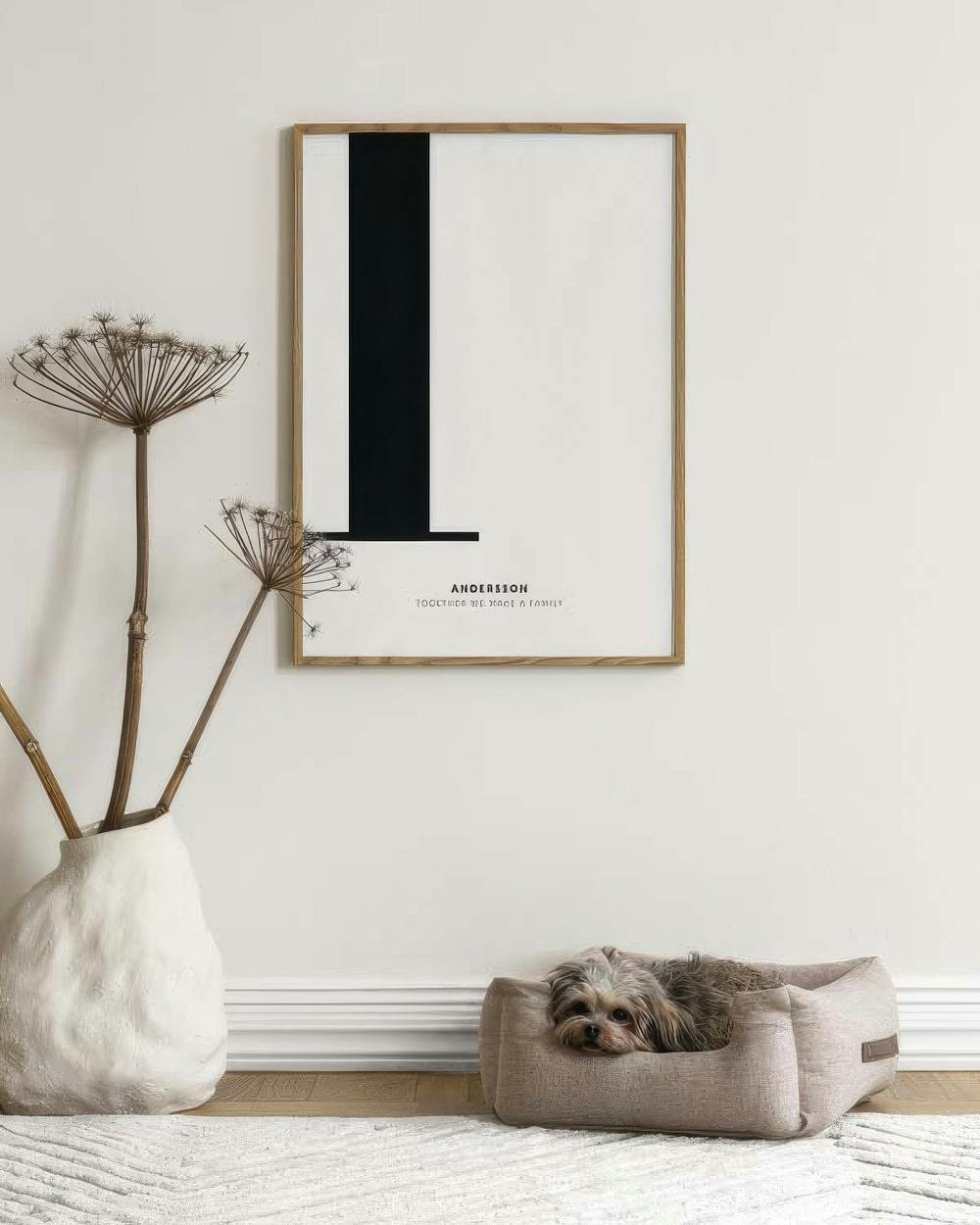 Personalised print with a large black letter L and family name, hanging above a small dog in a bed.