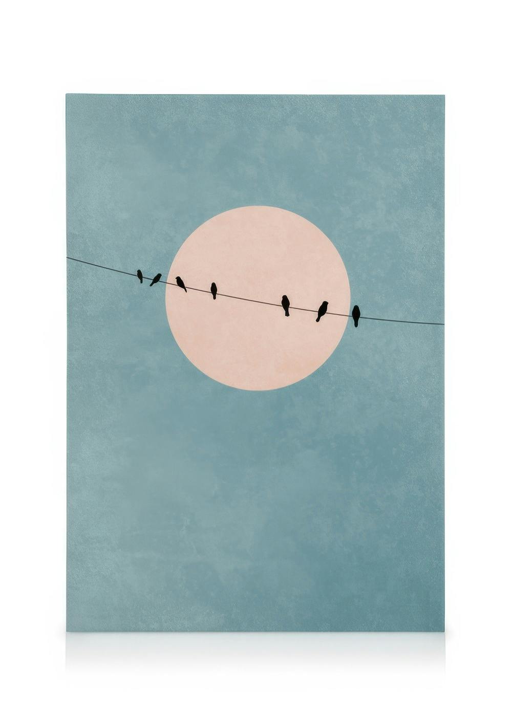 Minimalist canvas print with black bird silhouettes on a wire against a pale pink circle and muted blue background.