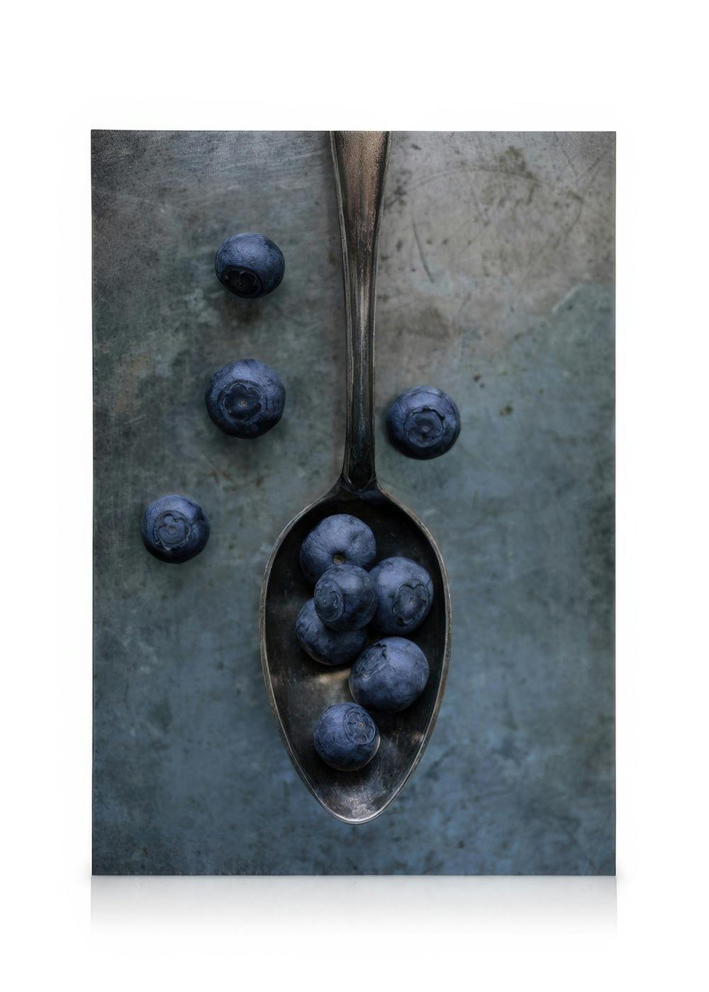 Sweet blueberries on a metal spoon against a textured blue-grey background, a close-up food canvas print.