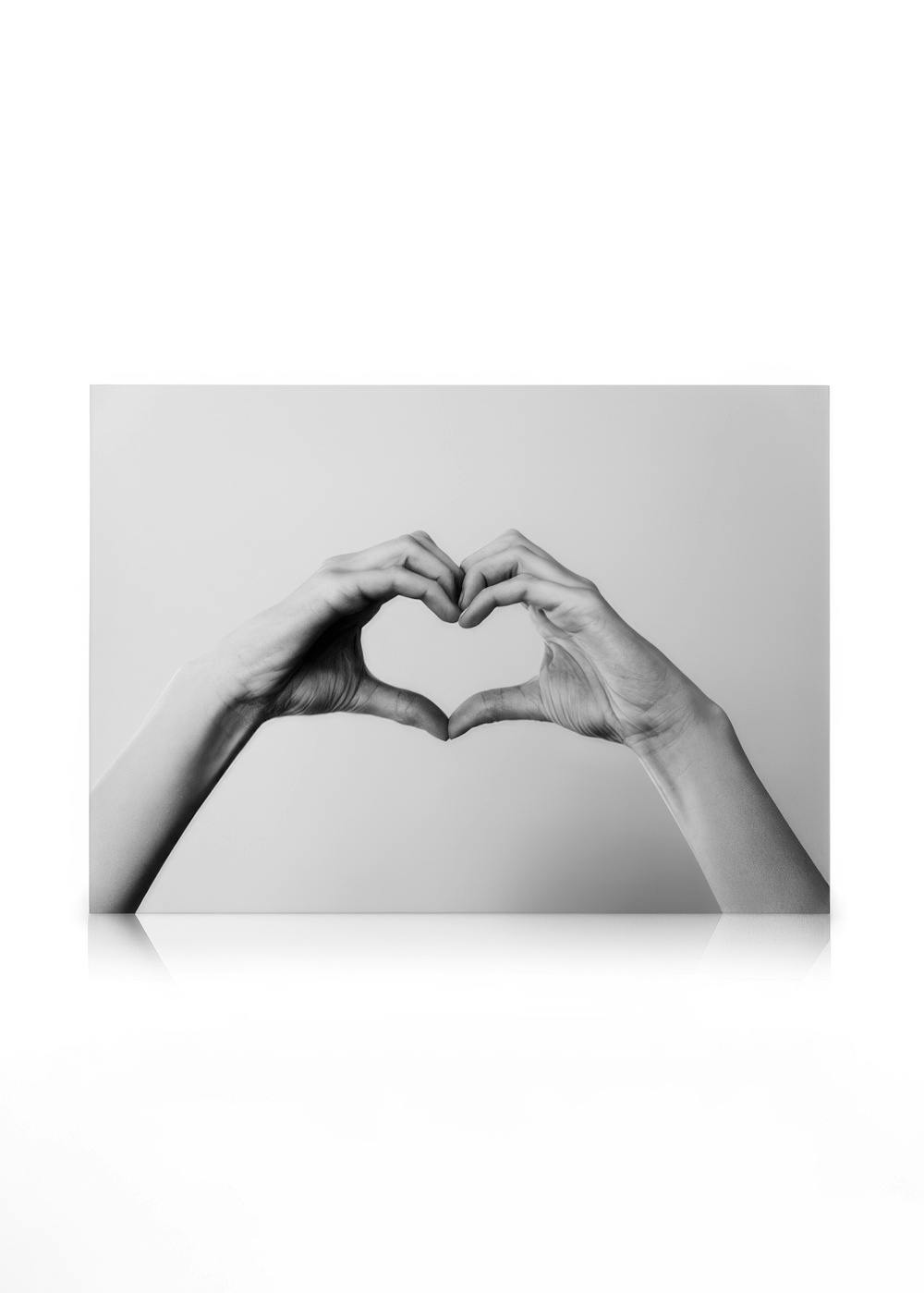 Black and white canvas print showing two hands forming a heart shape, symbolising love and connection.