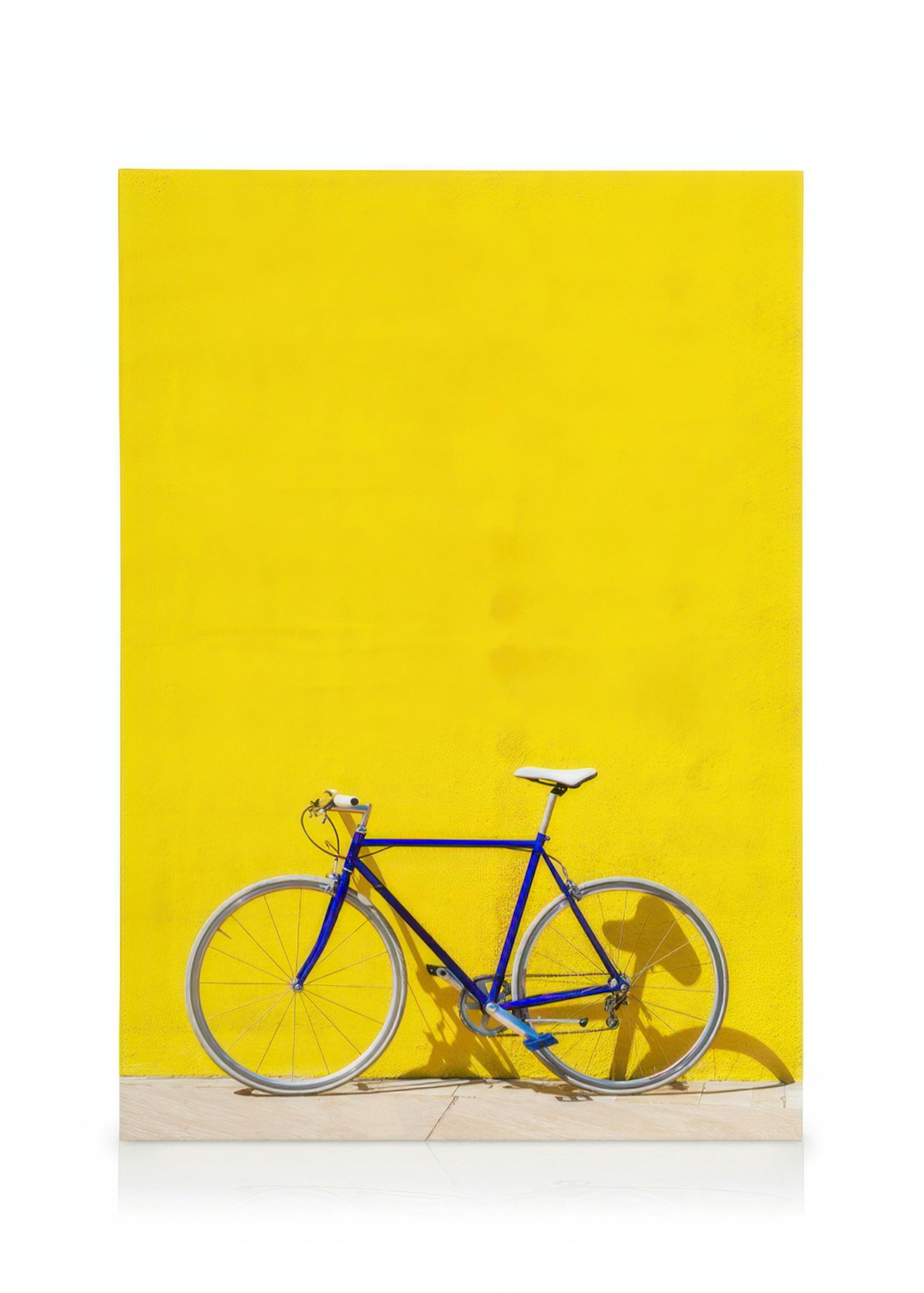 Vibrant yellow wall with a blue bicycle, modern art canvas print
