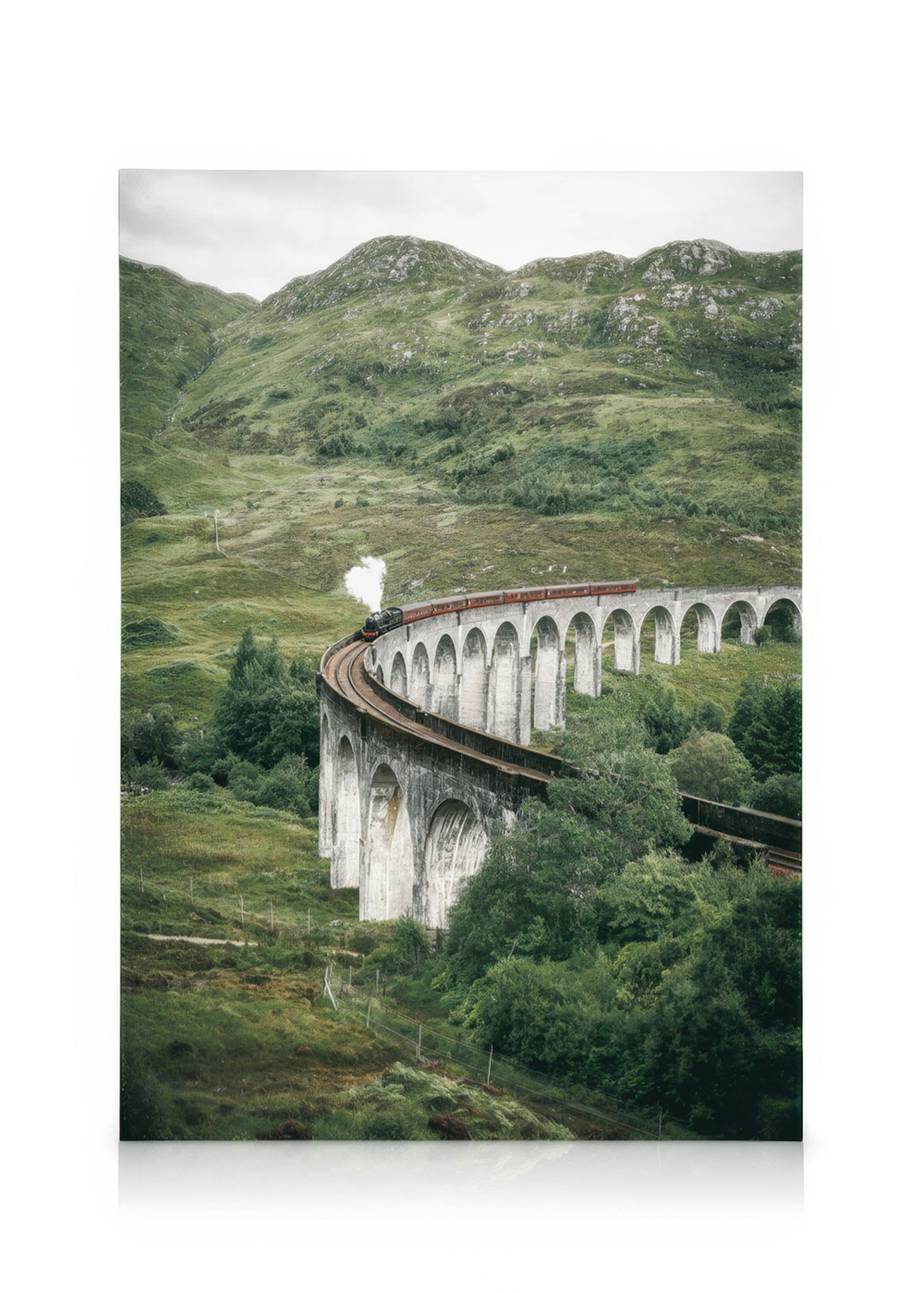 Steam train crossing the historic Glenfinnan Viaduct in the Scottish Highlands, surrounded by lush green hills.