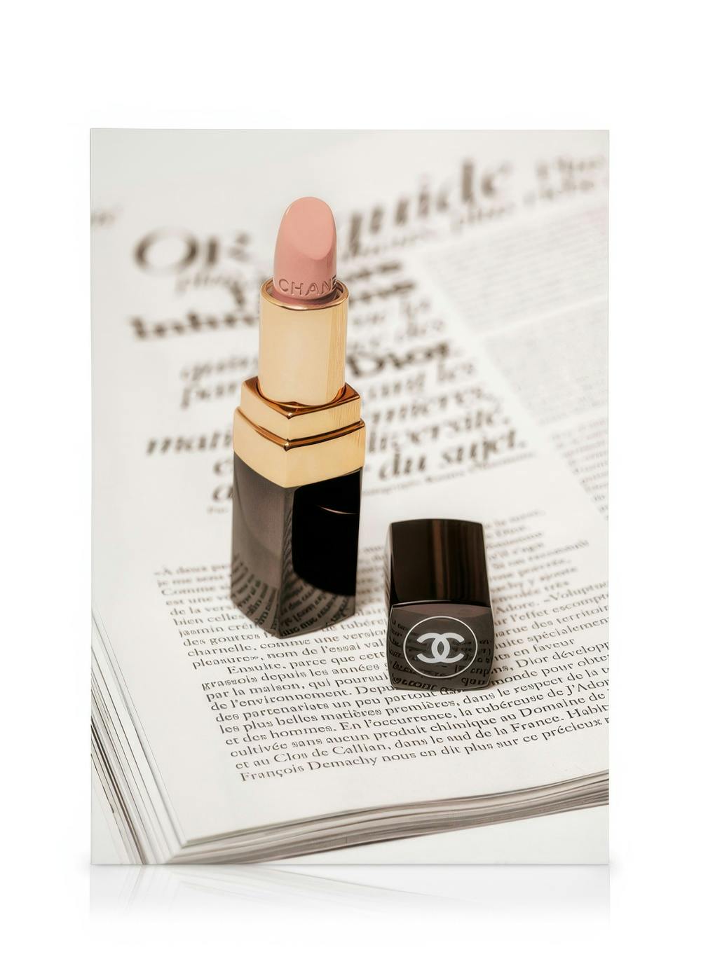 Pink Chanel lipstick and nail polish on an open magazine page, fashion-inspired canvas print.
