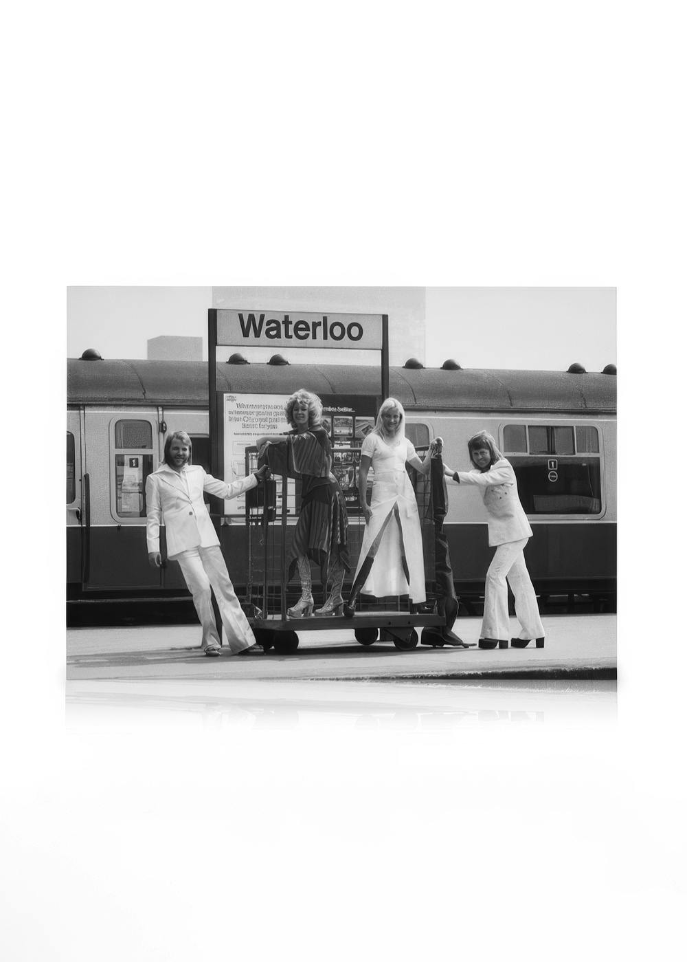 ABBA en blanco y negro posando con equipaje en la estación de Waterloo, Londres, estilo años 70.