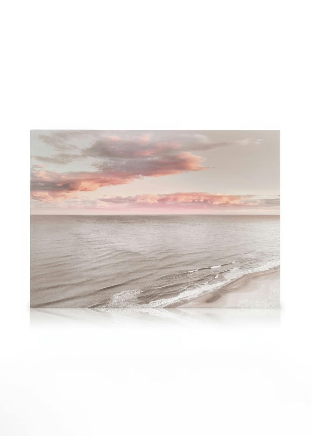 Dreamy sea canvas print featuring a serene beach with gentle waves under a sky of soft pink and grey clouds.