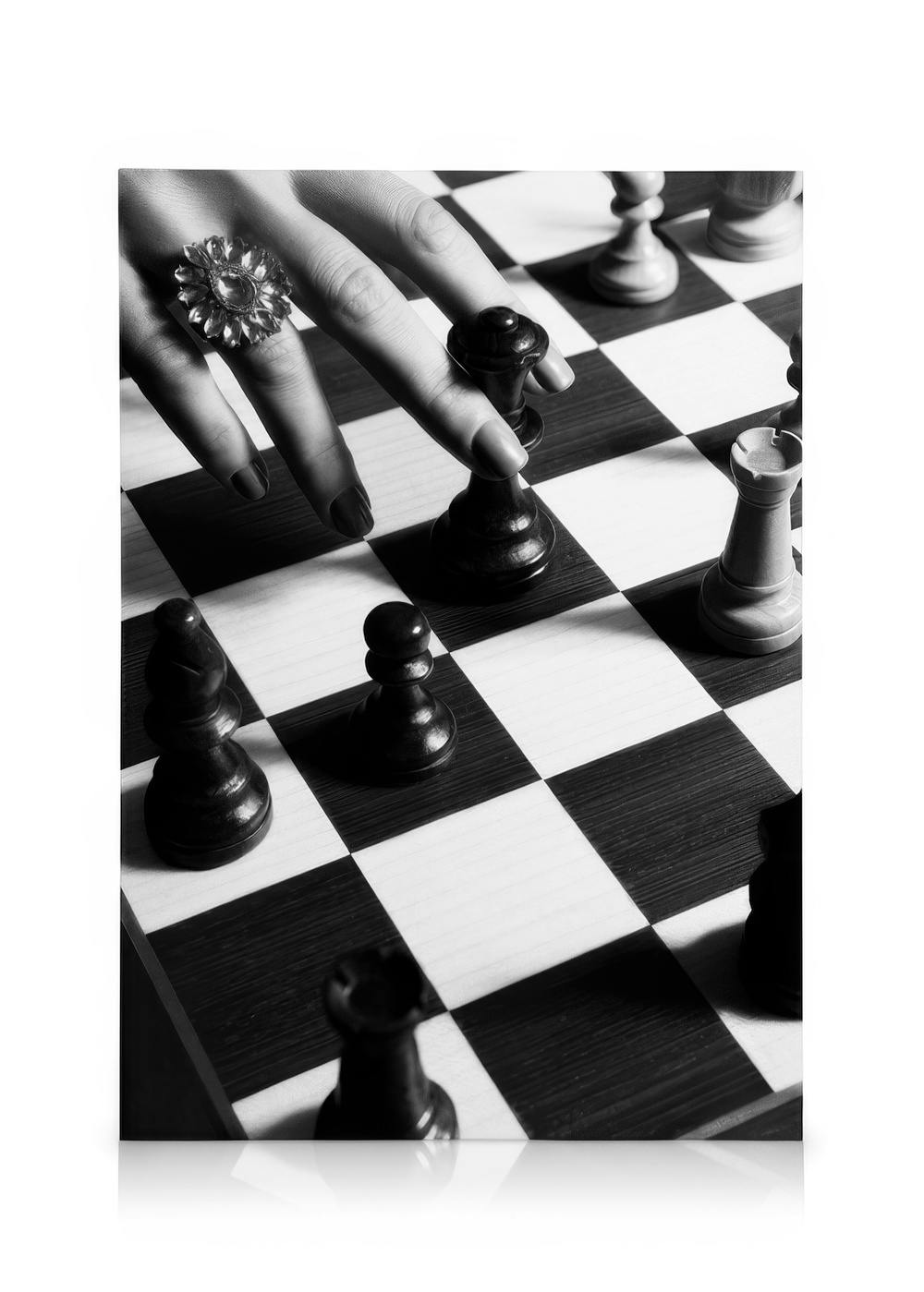 Schwarz-weißes Schachbrett mit Hand, die eine schwarze Schachfigur bewegt, eleganter Schmuckring sichtbar.