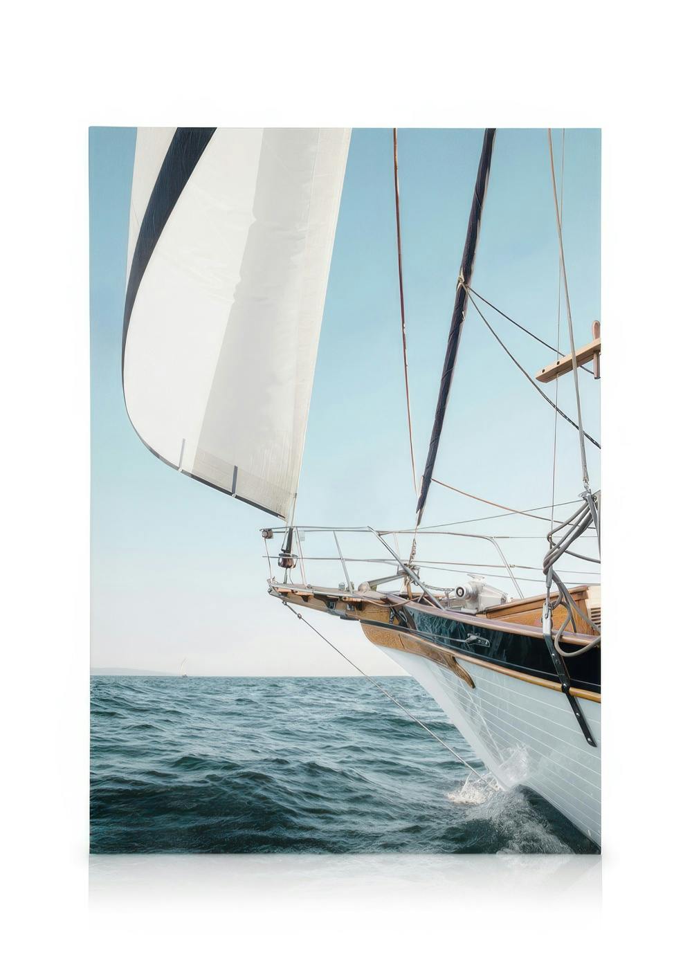 Toile dun voilier blanc et bleu naviguant sur une mer bleue sous un ciel clair, létrave coupant leau.