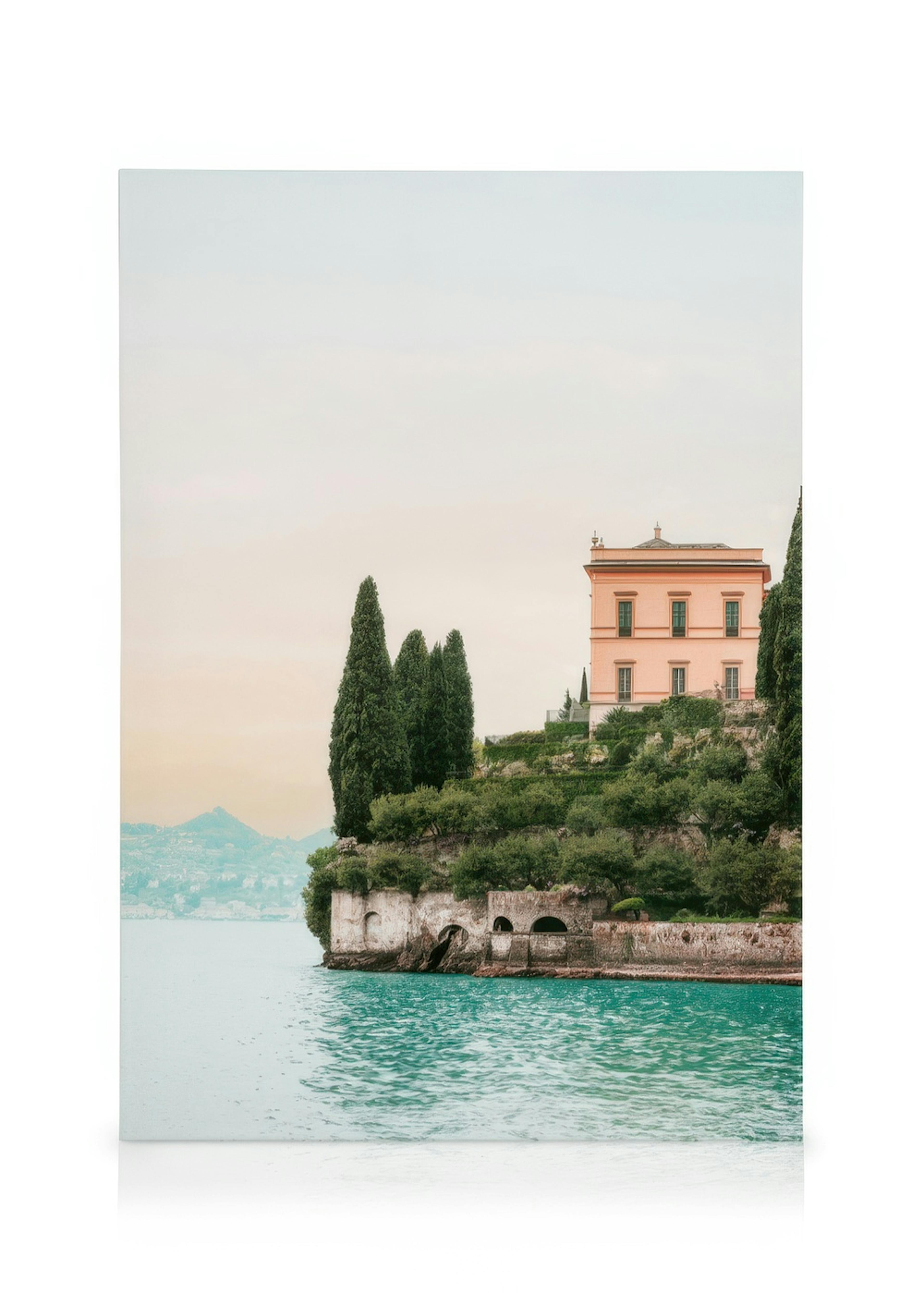 Villa Cipressi canvas print featuring a pink house on a green cliff above blue water, with distant hills.