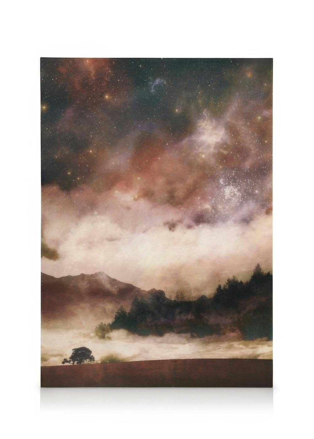 Stjärnklar natthimmel med röda, orange och lila nebulosor över dimmiga berg, skog och en träd-silhuett