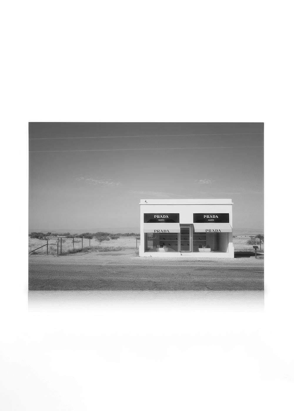 Tienda Prada Marfa en blanco y negro, edificio solitario en paisaje abierto con líneas eléctricas.