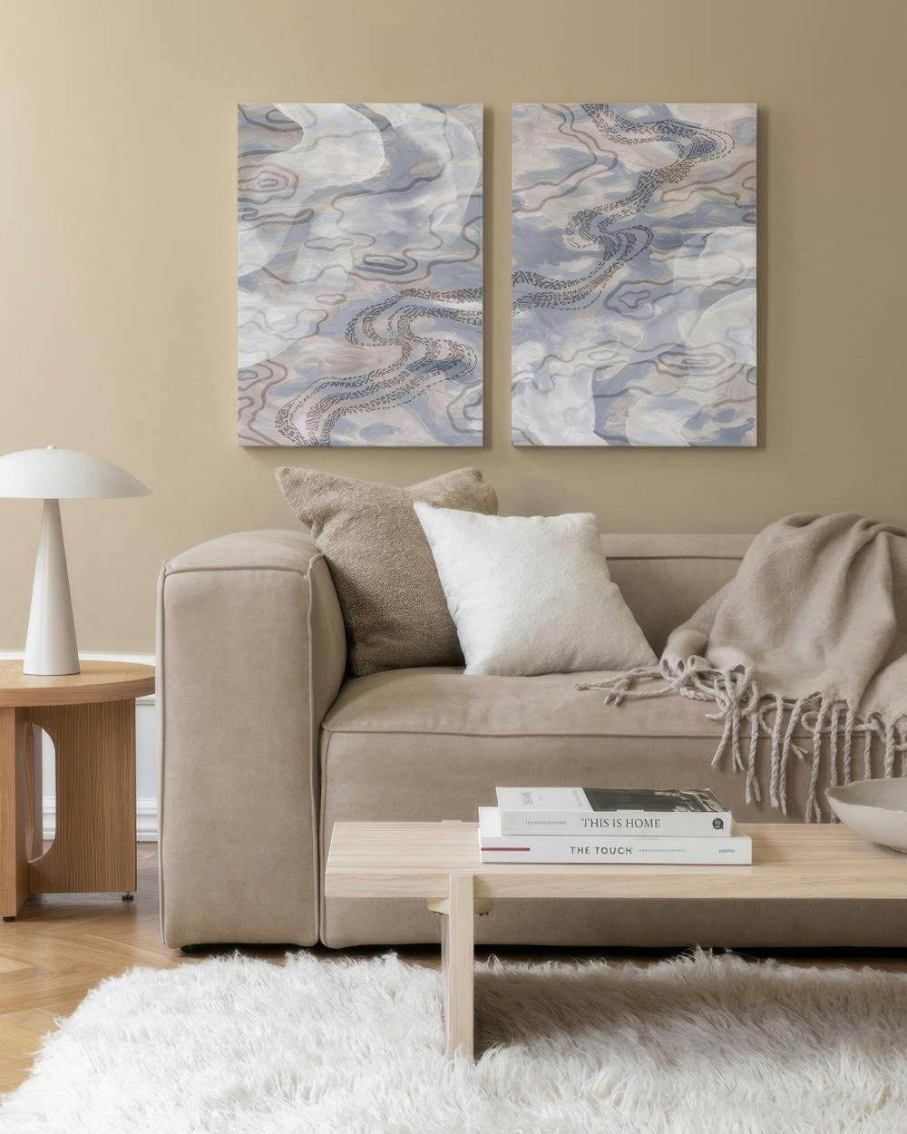 Abstrakte Leinwandbilder in Beige und Hellblau mit sanften Pinselstrichen, die eine ruhige, elegante Atmosphäre schaffen.