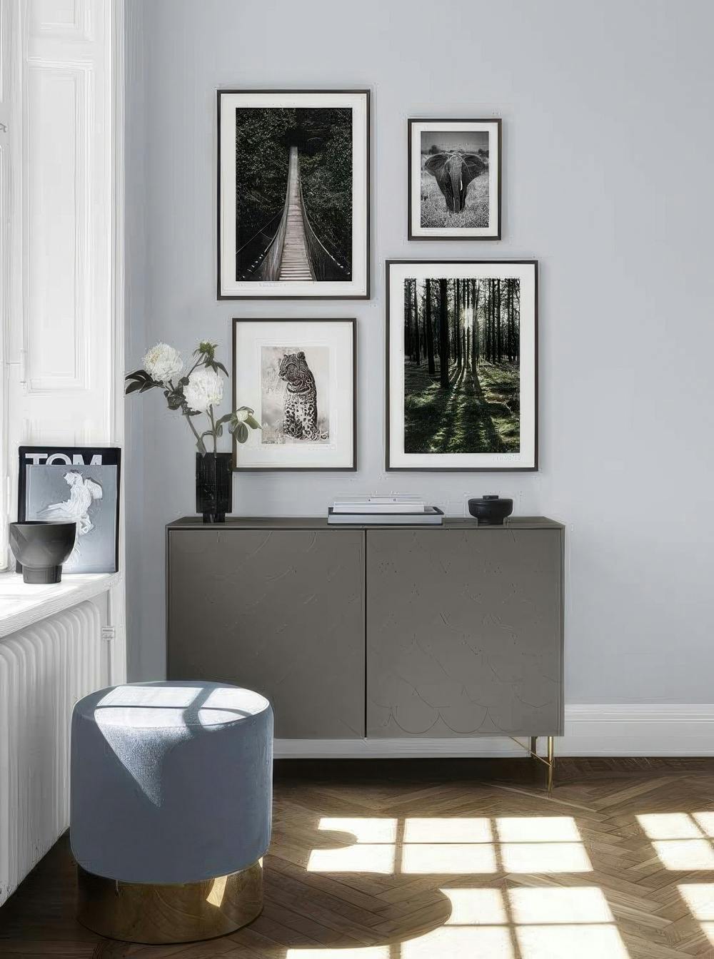 En tavelvägg med en hängbro bland träd, en elefant i gräs, en leopard och en skog med solstrålar.