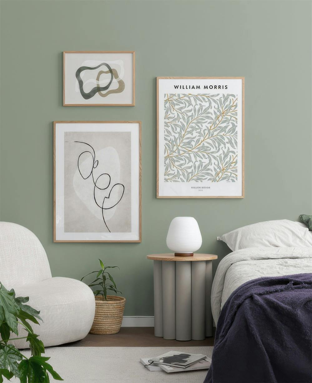 En tavelvägg med tre tavlor: en abstrakt form, ett linjeporträtt och ett William Morris-mönster.