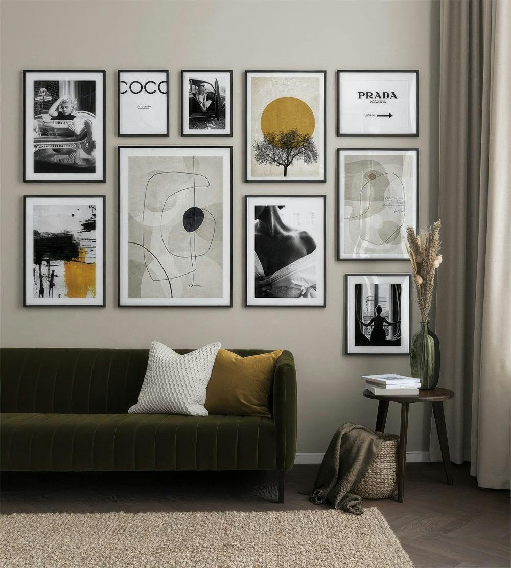 Una galleria a parete con stampe in bianco e nero, astratte e con soggetti di moda, e una stampa con albero e sole giallo.