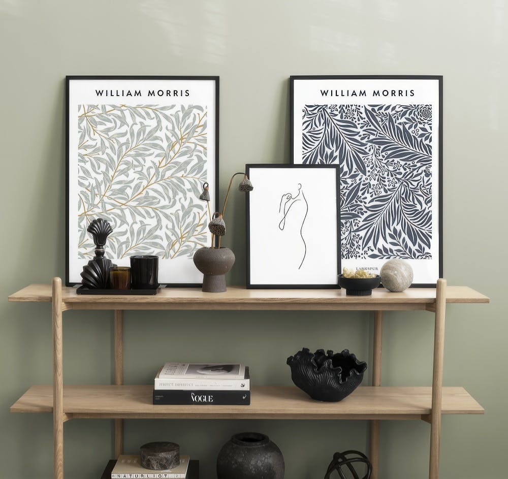 En tavelvägg med William Morris-mönster i gröna och blå nyanser, samt en linjeteckning av en kvinna.