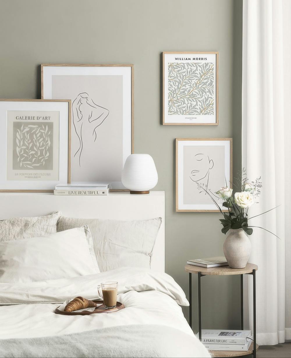 Una galleria a parete con stampe artistiche in stile linea continua e una stampa botanica William Morris, su una parete verde ch