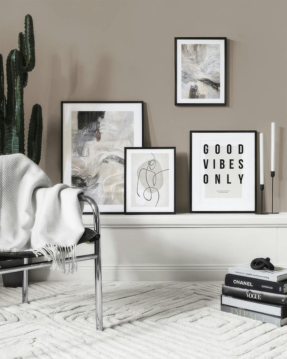 A gallery wall with three abstract prints in muted tones and a Good Vibes Only print, arranged on a shelf.