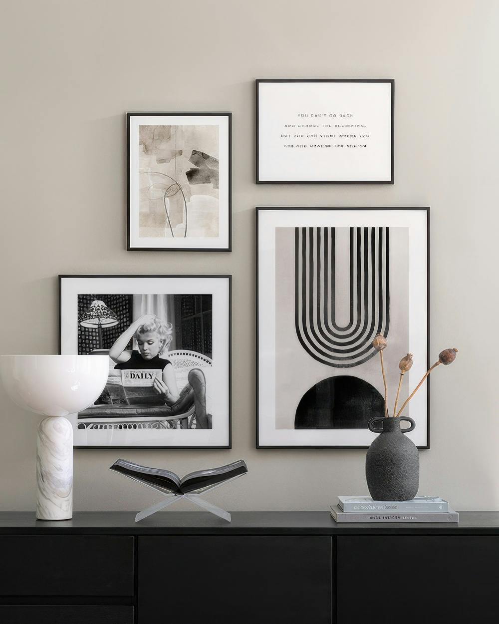 En tavelvägg med fyra svartvita posters: Marilyn Monroe, abstrakt form, citat och grafiskt mönster.