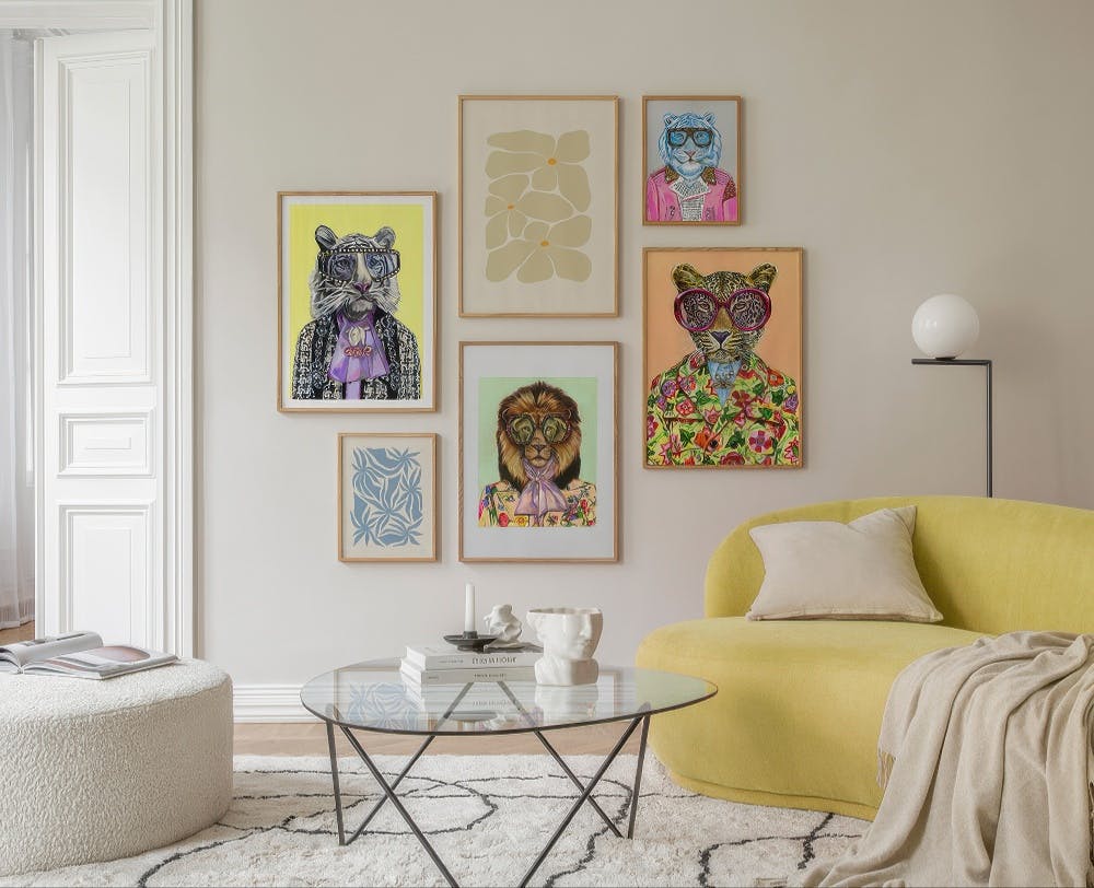 En tavelvägg med sju posters som föreställer djur i kläder, en abstrakt beige blomma och en blå växt.