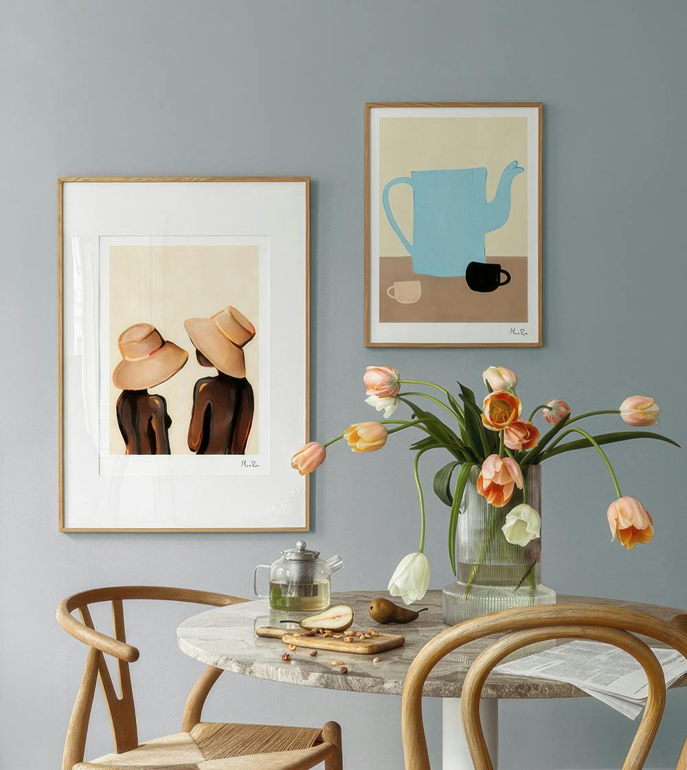 En tavelvägg med en bild av två kvinnor i hattar och en bild av en blå tekanna med två koppar.