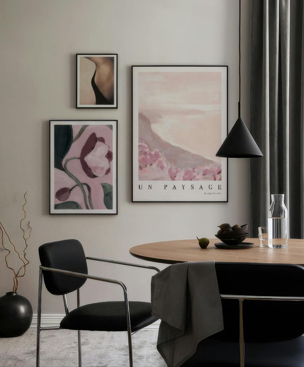 En tavelvägg med tre tavlor: en abstrakt bild av en kvinnlig rygg, en bild av rosa blommor och en rosa landskapsbild.