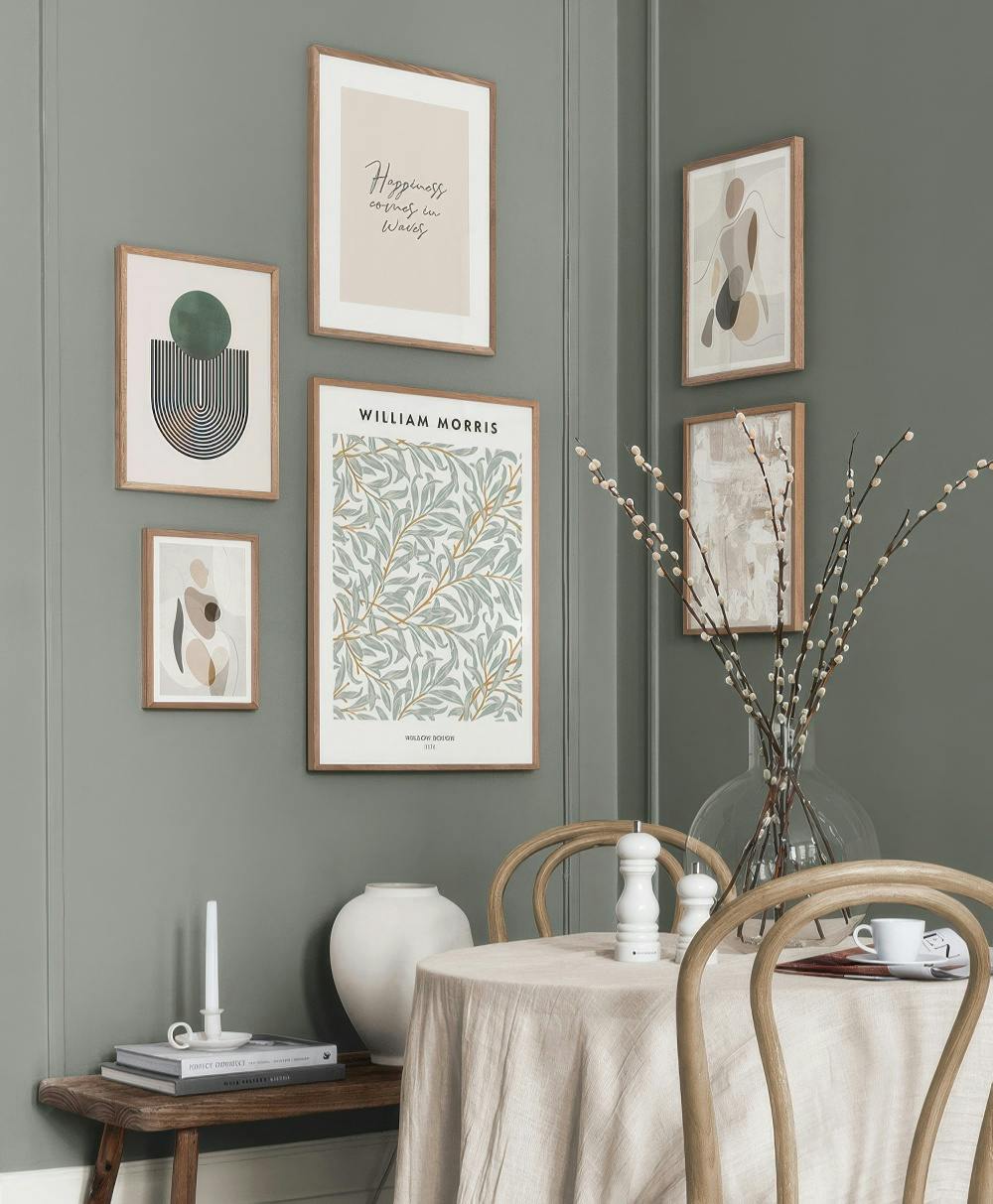 Una galleria a parete con stampe astratte in tonalità neutre e una stampa di William Morris su una parete verde.
