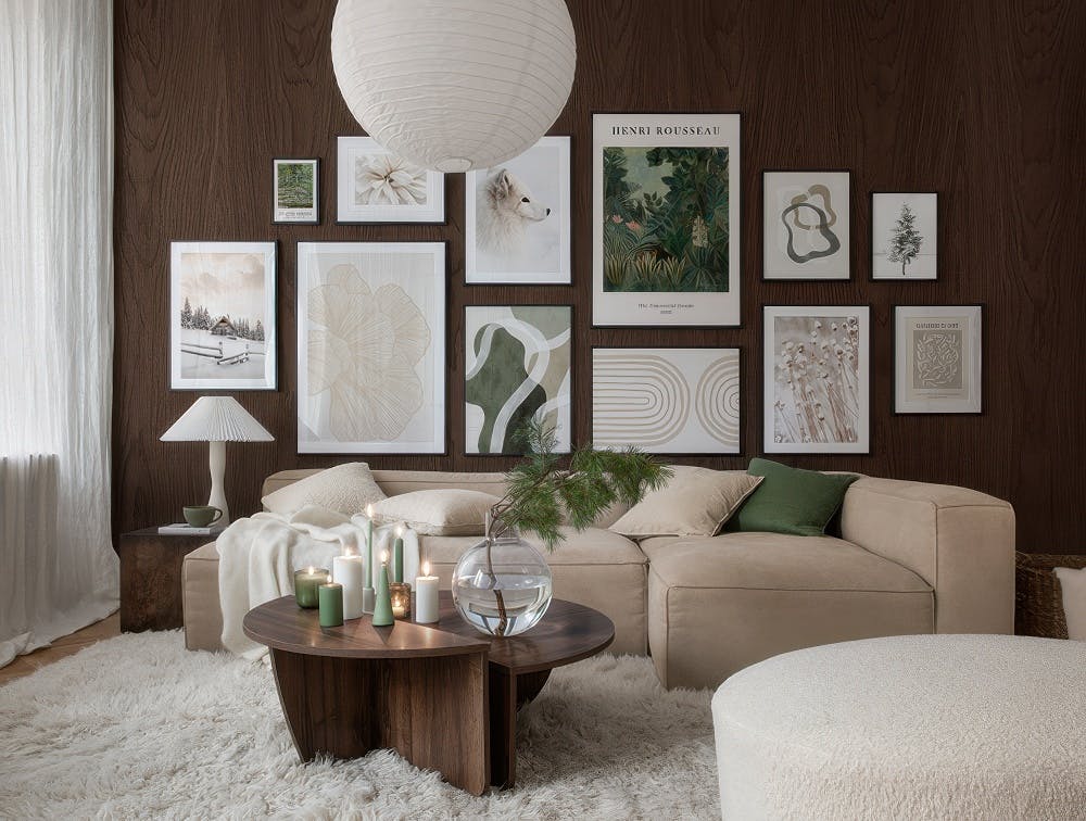 A gallery wall with a mix of nature-inspired prints, including a snowy cabin, a fox, abstract shapes, and botanical art, creatin