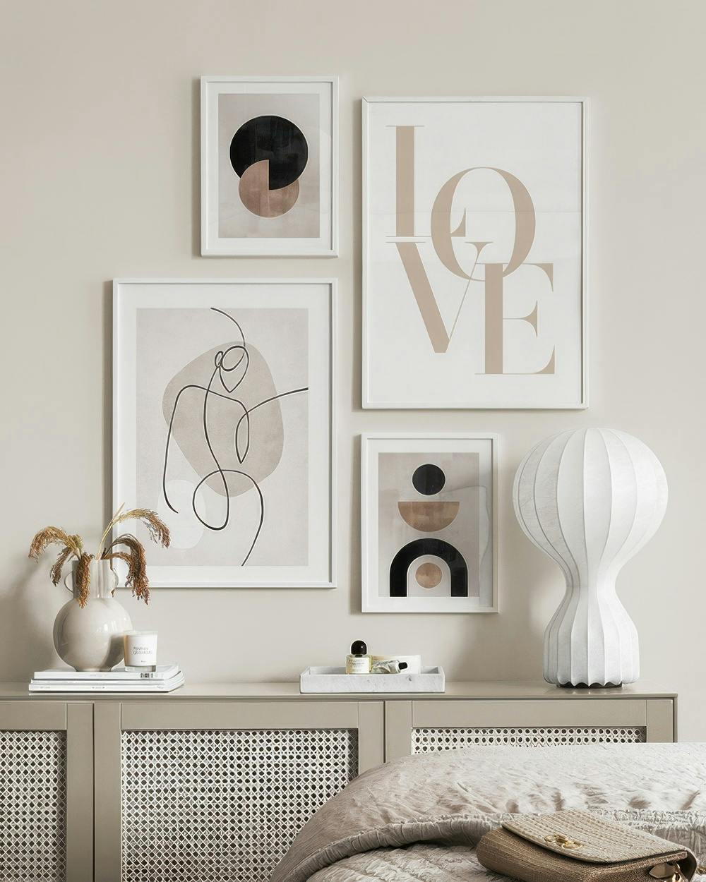 Eine Bilderwand mit beigen und schwarzen geometrischen Formen, schwarzen Linien und dem Wort LOVE in einem Schlafzimmer.