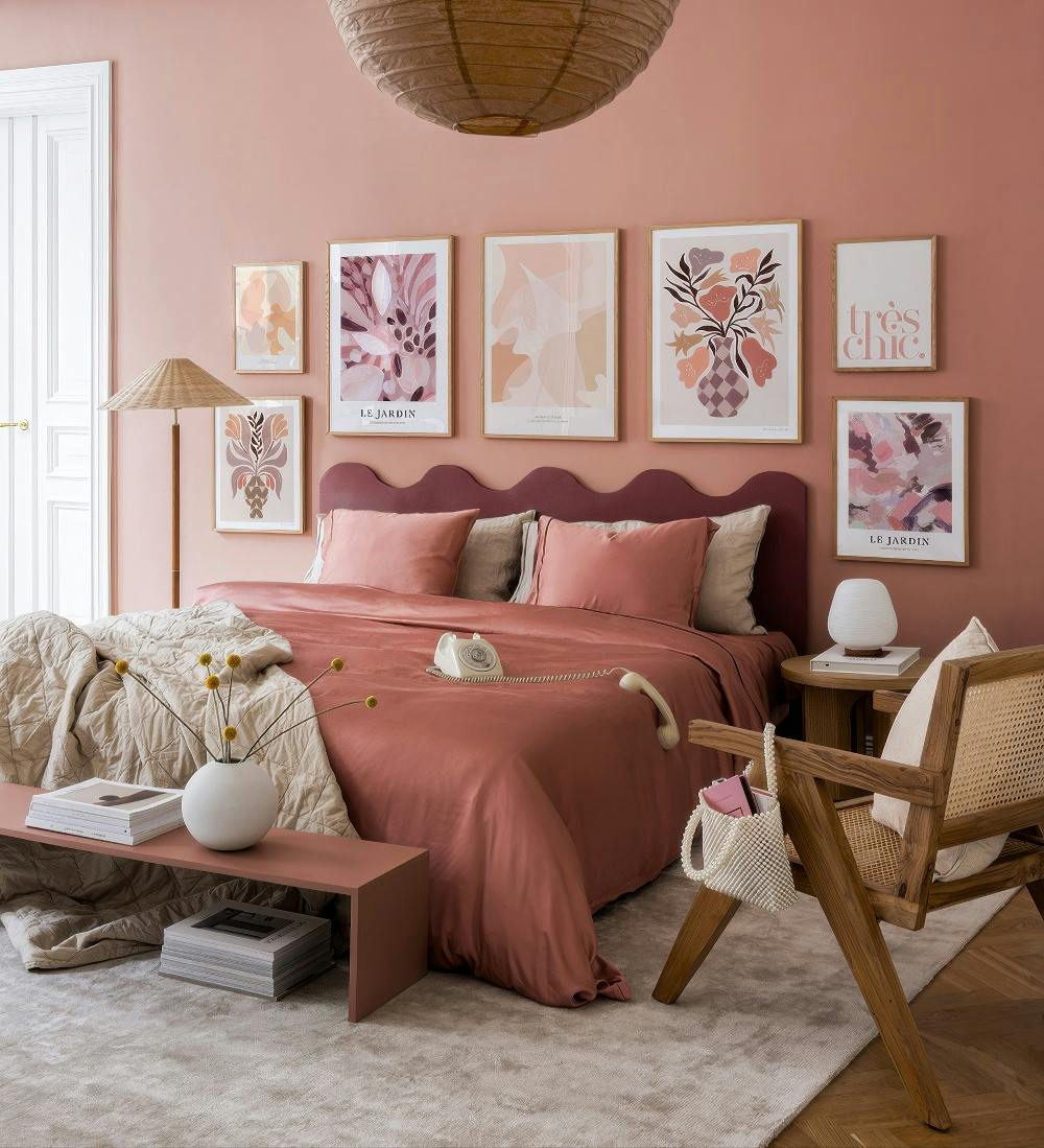 A gallery wall of six abstract botanical and text prints in pink, peach, and muted tones on a dusty rose bedroom wall.