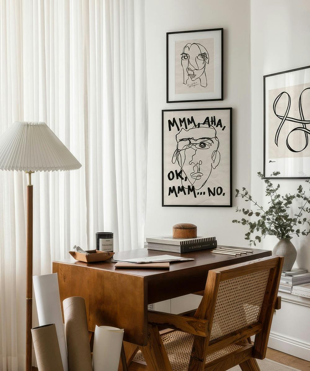 A gallery wall with three line art prints featuring abstract faces and a continuous line abstract design in a home office settin