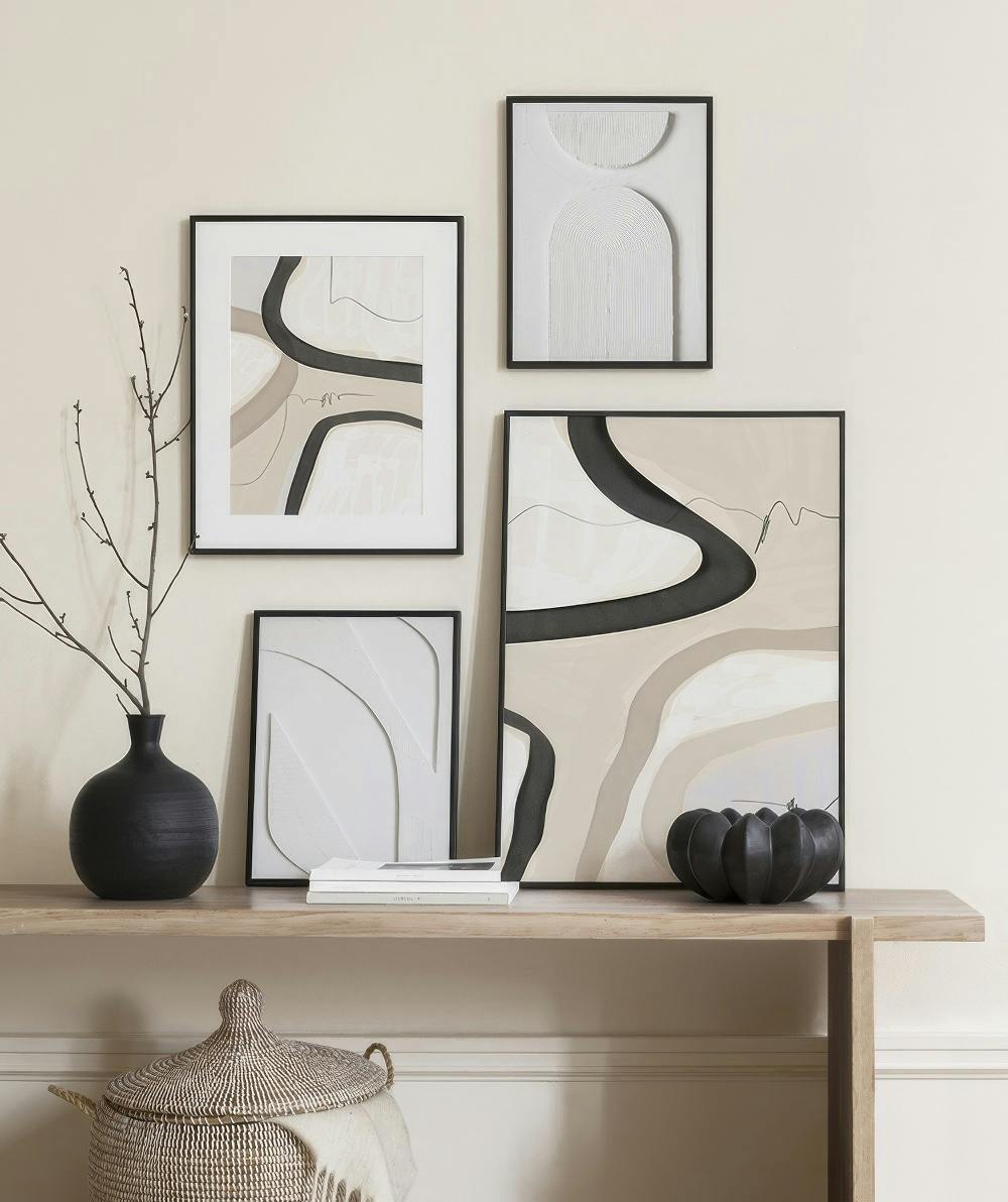 A gallery wall with abstract art featuring beige, black, and white organic shapes, with textured white wall art.