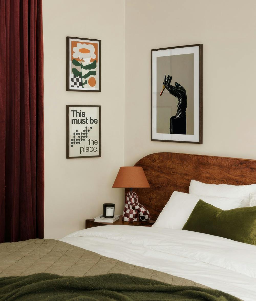 A gallery wall featuring a modern floral print, a typographic print with checkerboard, and a stylish hand holding a cigarette.